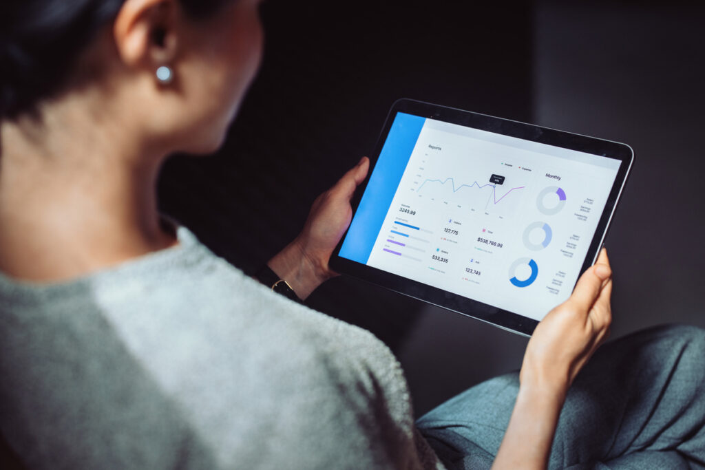 Vrouw bekijkt financiële grafieken en dashboards op een tablet